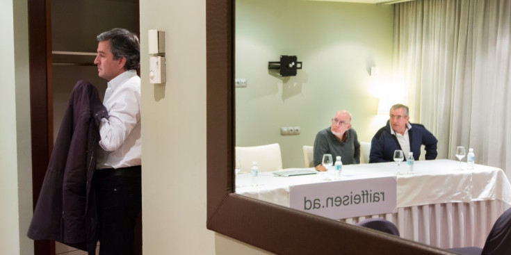 A la porta, l’economista Eusebi Nomen, i reflectits al mirall, dos membres de la cooperativa raiffeisen, Xavier Feliubadaló i Antoni Sánchez, ahir en roda de premsa.