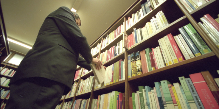Un home busca un llibre a les prestatgeries de la Biblioteca Pública del Govern.