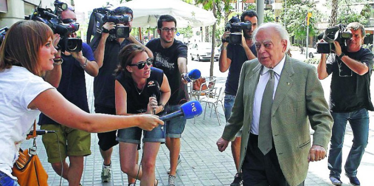 Pujol, camí de declarar, envoltat de periodistes.