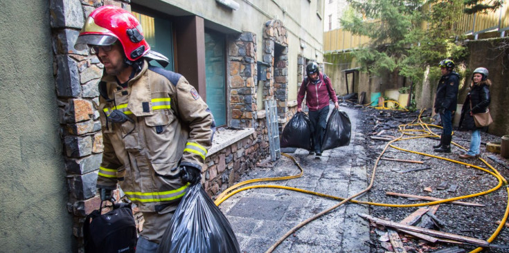 Bombers i veïns retiren els objectes personals dels residents dels habitatges, ahir.