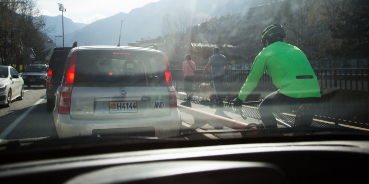 Un ciclista envoltat de cotxes, ahir a l’avinguda de Salou, fotografiat des de la part de darrere d’un vehicle.