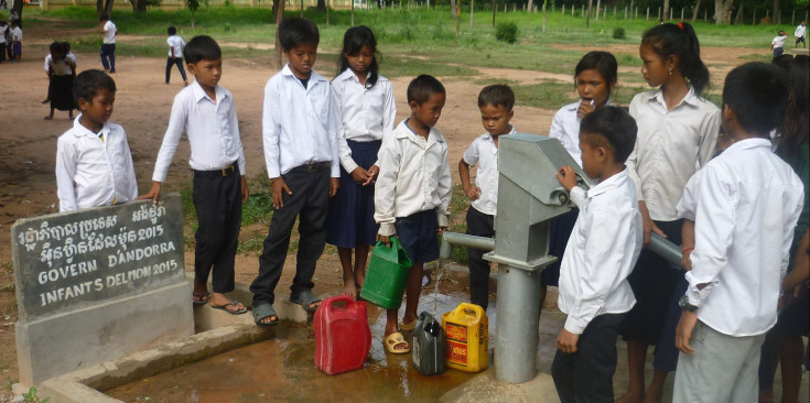 Grups de nens i nenes treuen aigua dels pous construïts per Infants del Món.