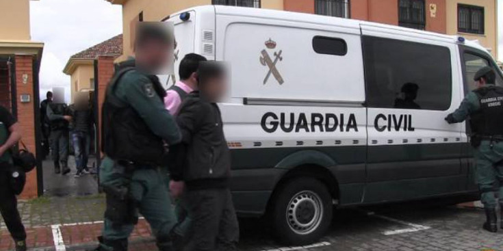 Agents de la Guàrdia Civil espanyola acompanyen a un dels proxenetes detinguts a introduir-se en el furgó del cos.