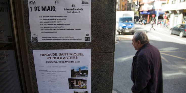 Un home passa per davant d’un cartell amb els actes de l’1 de maig.