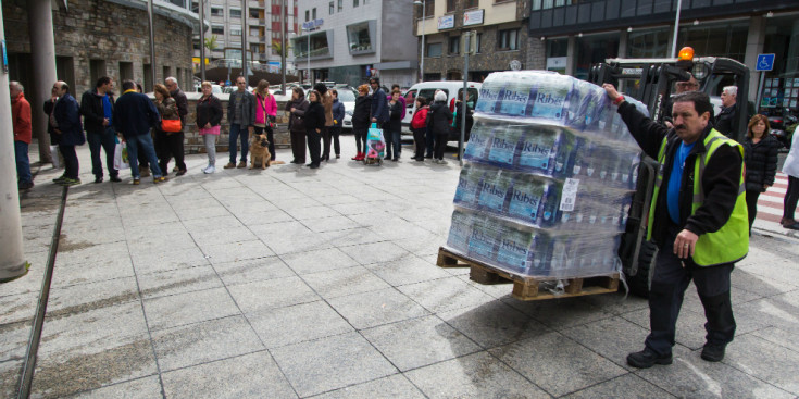 Uns empleats del coú transporten un palet amb pacs d'ampolles d'aigua per repartir entre la població escaldenca, ahir.