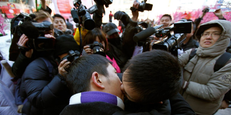 Una parella de nois xinesos es fa un petó a Pequín el dia de Sant Valentí, mentre una allau de reporters gràfics els fan una fotografia.