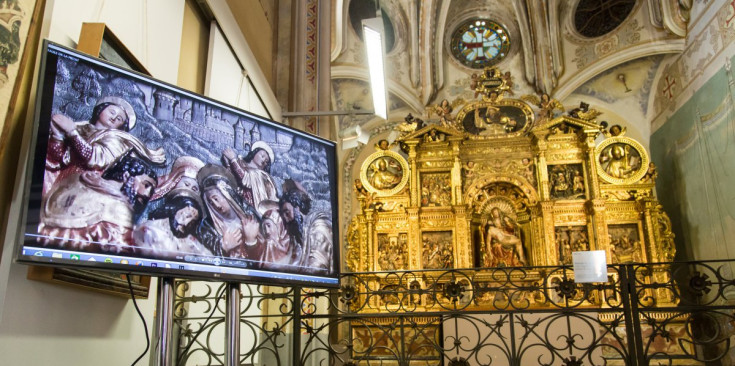 En primer pla, l’audiovisual sobre el procés de restauració del retaule projecta un detall de la taula del davallament de la creu i, al fons, es pot observar el retaule de la Pietat sencer, ahir.