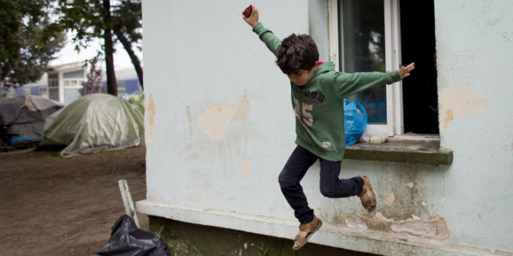 Un nen salta des d’una finestra, ahir en el camp de refugiats d’Idomeni.