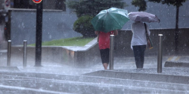 Dues persones caminen sota la intensa pluja.