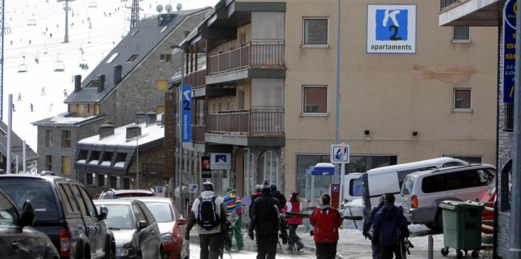 Un grup d’esquiadors passegen davant d’uns apartaments d’ús turístic al Pas de la Casa.